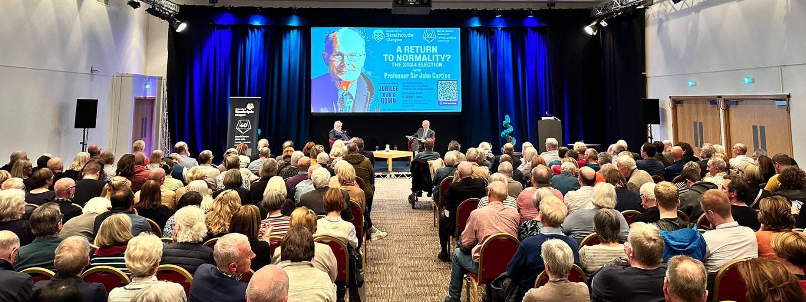 An audience watches a talk with Professor Sir John Curtice