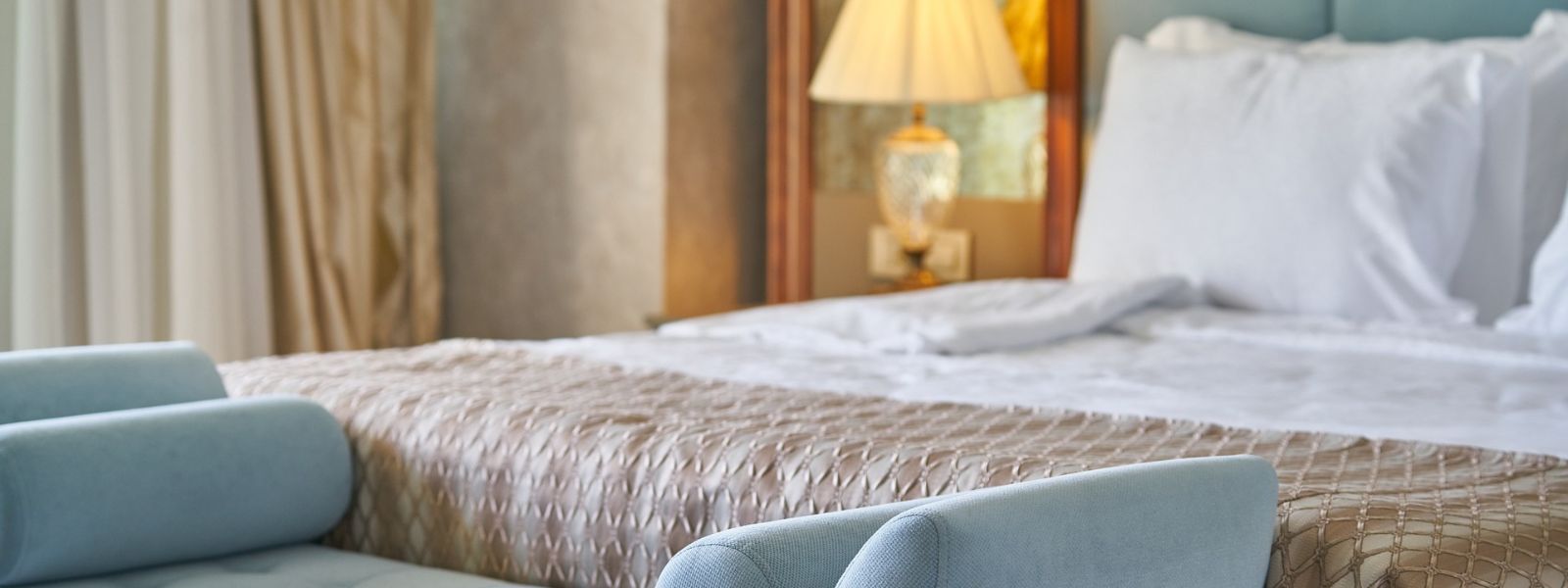 A hotel room interior with bed, lamp and sofa A hotel room interior with bed, lamp and sofa