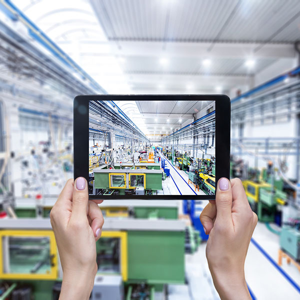 Close-up image of female hands holding digital tablet in modern factory. 