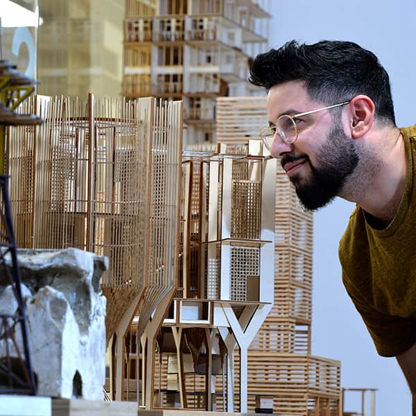 Student examining a model of a building.