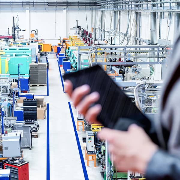 Woman standing on top of a balcony in a factory holding a touchpad.