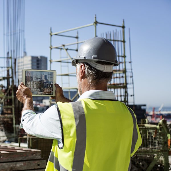 Architect photographing construction site on digital tablet