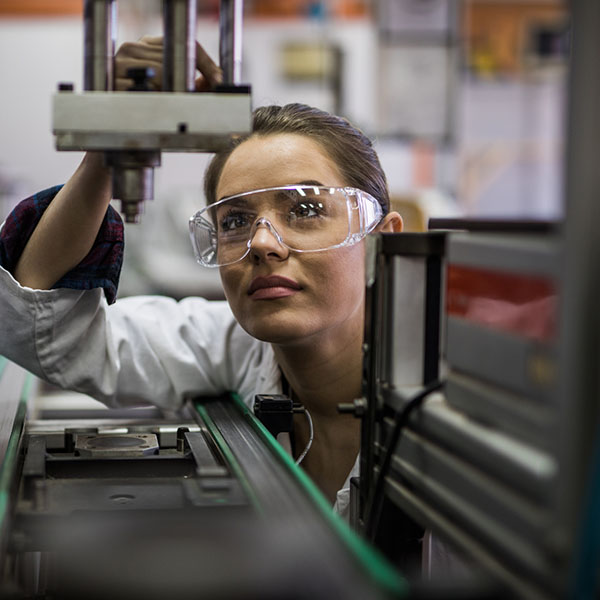 Female engineer examining machine part on a production line