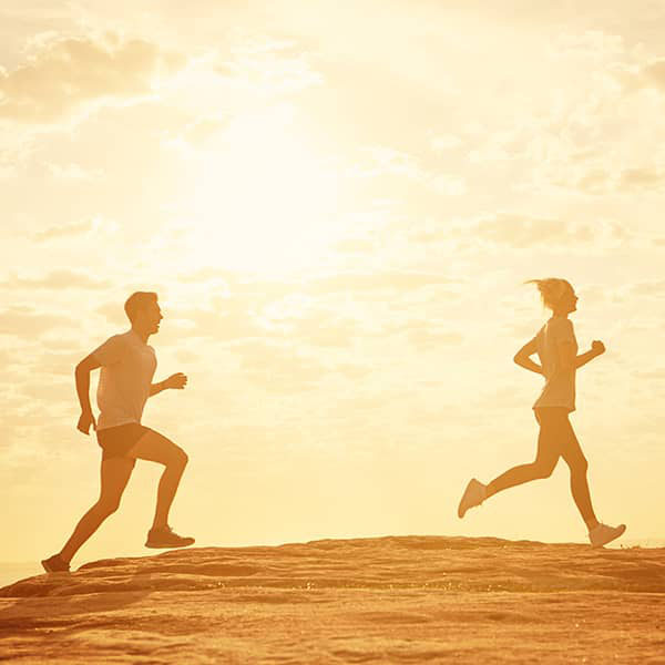 Two people running at sunset