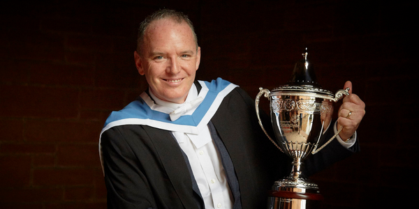 Adrian Gillespie hold his Alumnus of the Year trophy