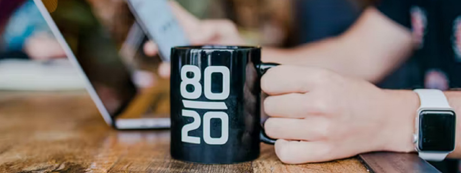 A hand holding a mug that says 80/20