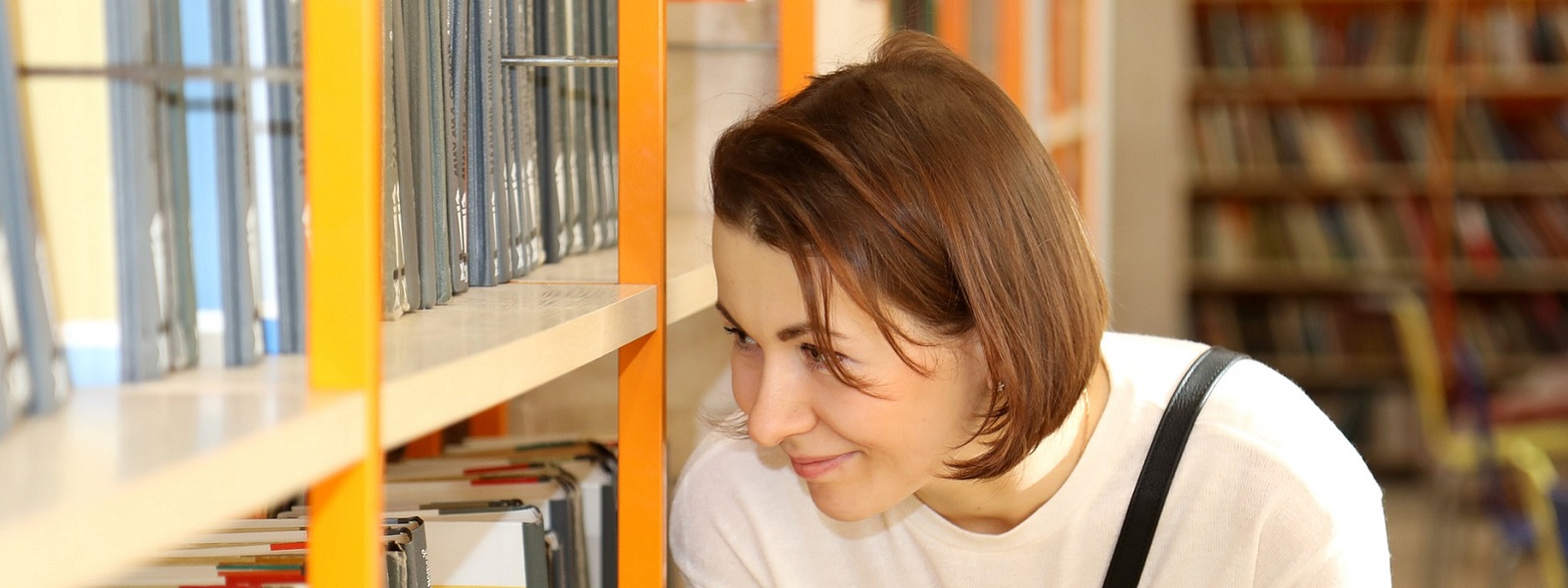 A student looking at shelves of books in the library