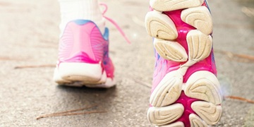 Rear view of a pair of feet walking in pink trainers
