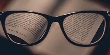 A pair of glasses sitting on the pages of an open book