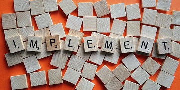Scrabble tiles spelling out 'implement'