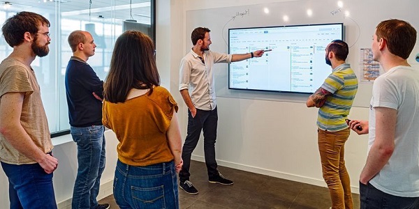 People standing around a screen on a wall