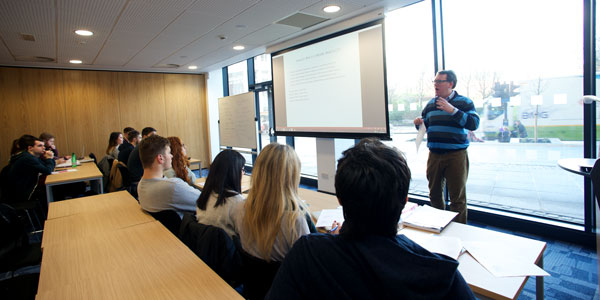 a lecturer delivers a lecture to a small class