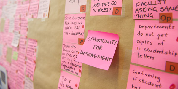 post it notes on the wall, the centre post it states 'opportunity for improvement'