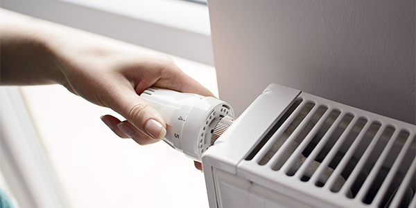 A hand turning the control on a heater