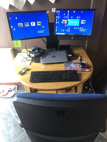 A complete computer set up and chair at a dinner table