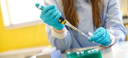 a female researcher using a device to inject a sample into a small container