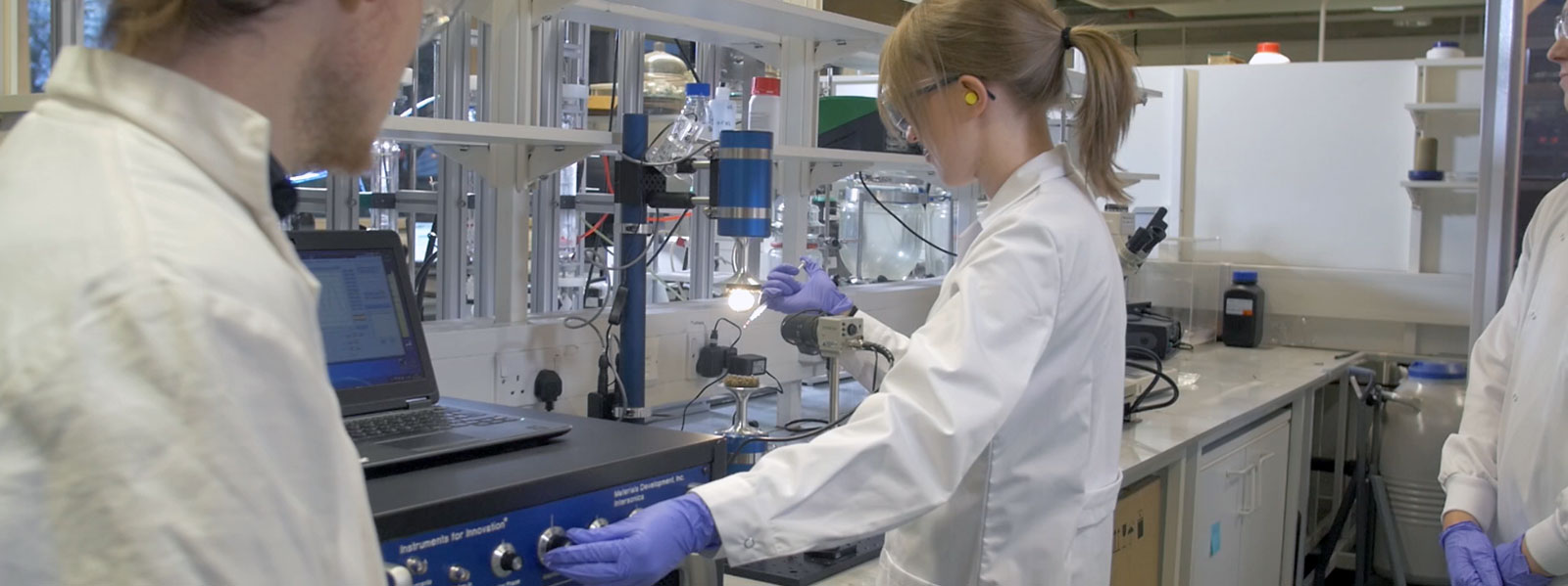 Scientists working in a CMAC laboratory in white lab coats and glasses