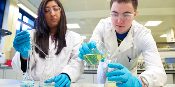 two chemistry students carrying out an experiment in a lab