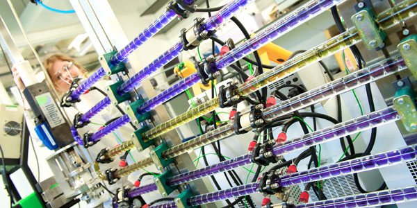 a scientist works with pipes filled with colourful liquids