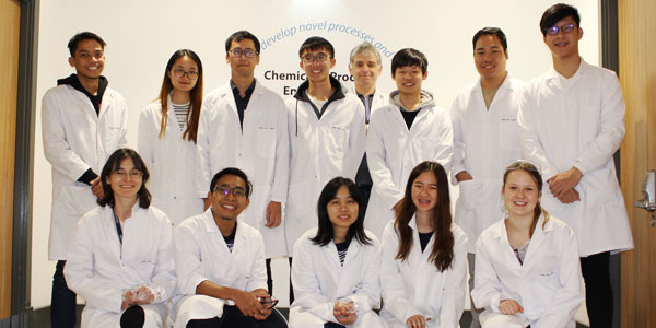 Summer school students wearing lab coats smiling at the camera