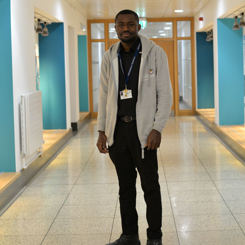 PhD student Precious standing in the James Weir corridor smiling at the camera