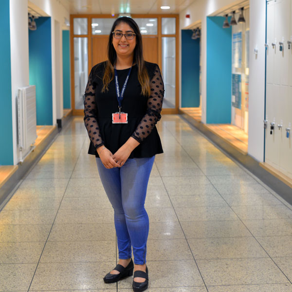 PhD student Aditi standing in the James Weir corridor smiling at the camera