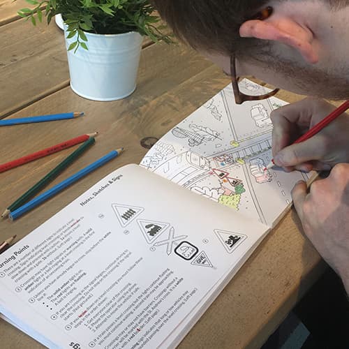 A person using a Theory Test educational colouring book 