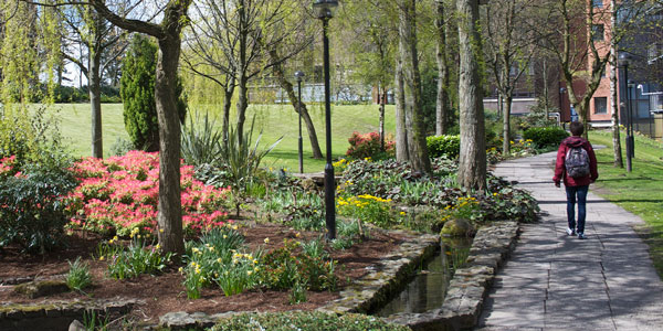 student walking through the gardens on campus