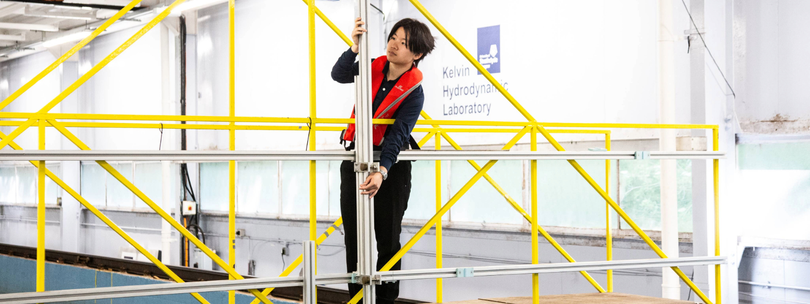 A student holding a metal pole above a water tank