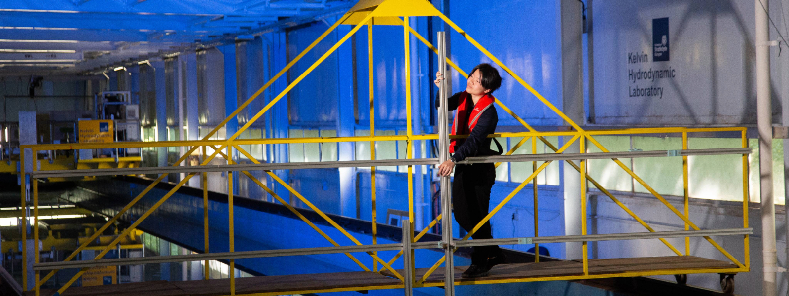 A student holding a metal pole above a water tank