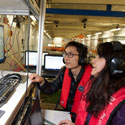 close up of students analysing data on a computer, stationed on the platform over a water tank