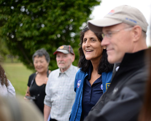 Suni Williams is in focus while standing next to colleague Rick Scheuring who is out of focus chatting to a group of Space School students Suni Williams is in focus while standing next to colleague Rick Scheuring who is out of focus chatting to a group of Space School students