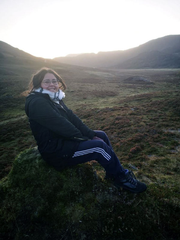 Rocio sitting on a rock in the Scottish hills