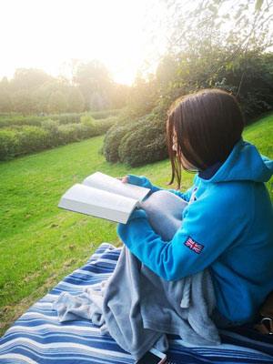 Rocio sitting on the grass reading a book