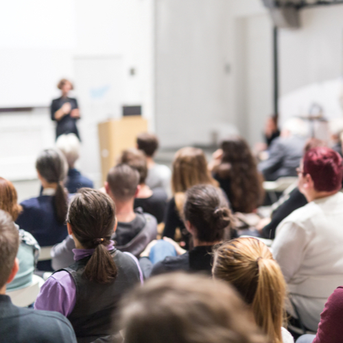 Female speaker giving presentation in lecture hall at workshop.