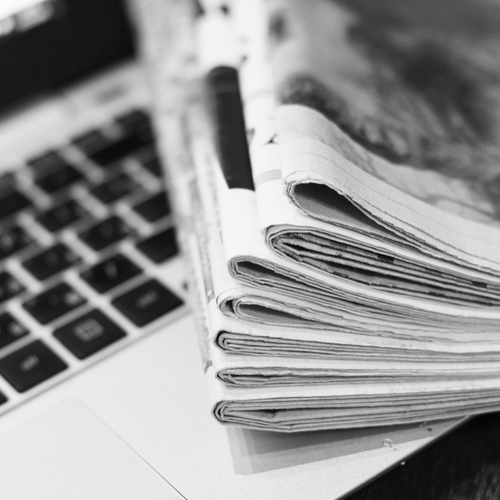 Newspapers piled on top of a laptop
