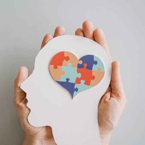Hands holding jigsaw puzzle heart shape in brain