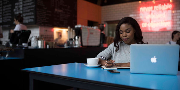 A student writes in a notepad inside a cafe