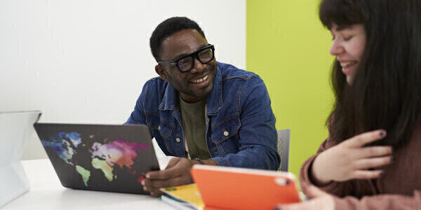 Two students studying together in the library using a tablet device