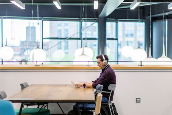 A photo of Strathclyde student sat at a table using a laptop to study in the Learning and Teaching building
