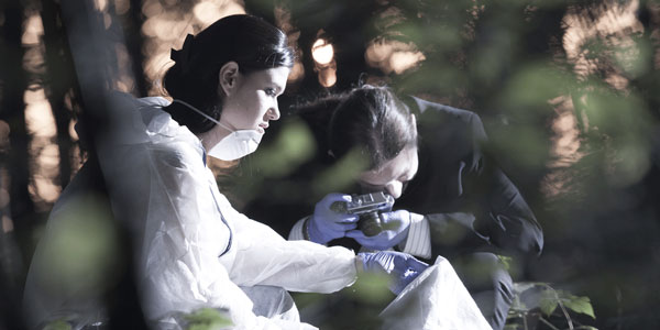 a crime scene investigator in a white protective suit and a forensic photographer take a photo on a crime scene