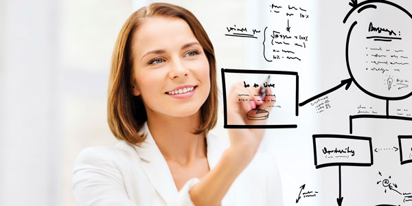 a woman writes on a clear board with a black marker