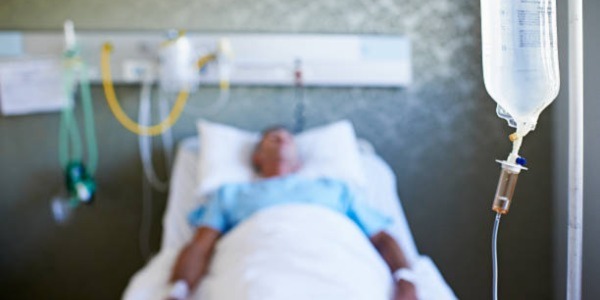 Man lying in hospital bed with a drip