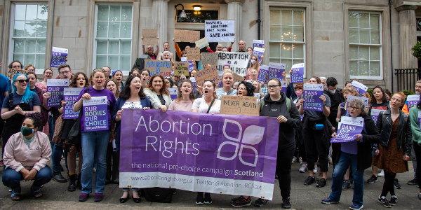 People attending an abortion rally behind a banner
