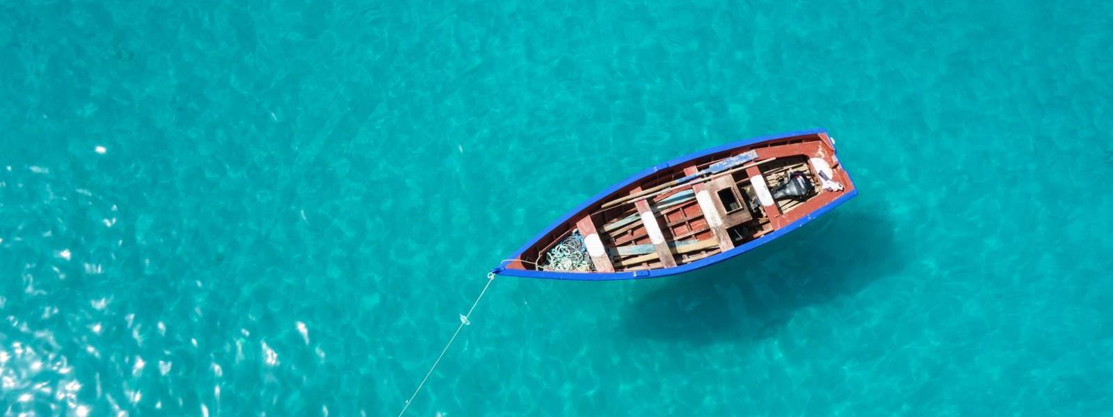 A boat floats on the bright blue ocean