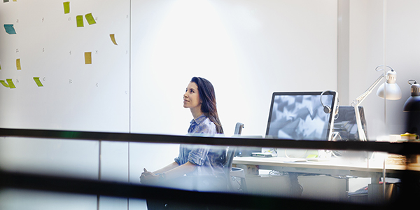 Woman looking at post-it notes on glass wall in office