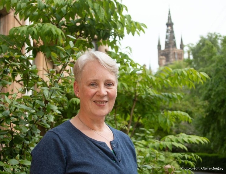 Professor Stuart-Smith standing in front of some trees and the University of Glasgow towe.