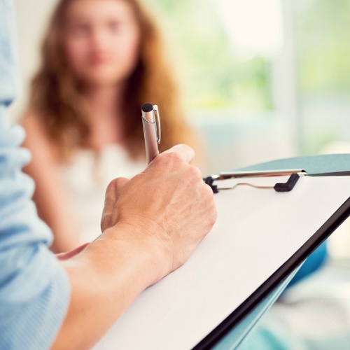 Hand of counsellor with clipboard facing patient 