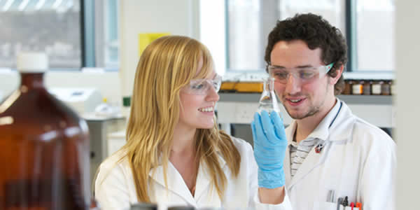 Two science students looking at a conical flask