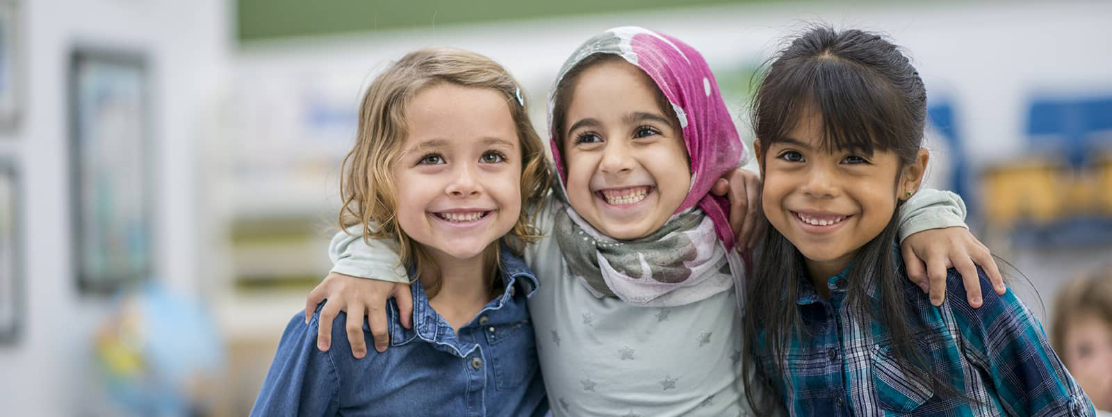 Three schoolgirls smiling in a classroom